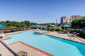 a swimming pool with chairs and umbrellas and a building in the background at East 51 At Rocketts Landing, Virginia